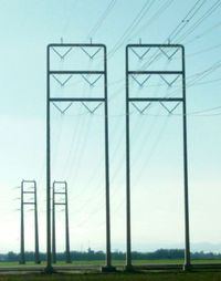 Electricity pylon on field against clear sky