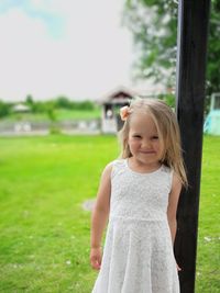 Portrait of girl standing on grass against sky