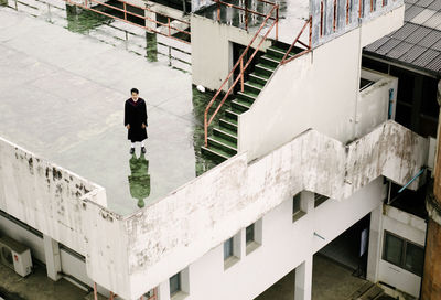 High angle view man in graduation gown standing on building terrace