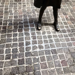 Low section of man walking on cobblestone street