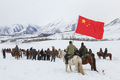 People riding horse on snow covered landscape