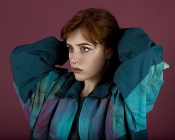 Close-up young woman looking away against brown background