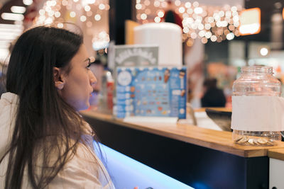 A young girl stands behind a counter in a shopping mall.