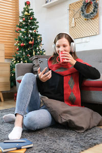 Low section of woman using mobile phone while sitting on sofa at home