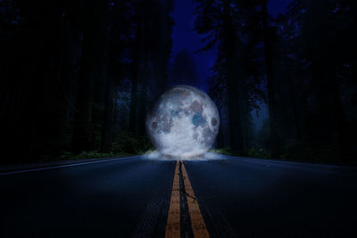 Digital composite image of road amidst trees at night