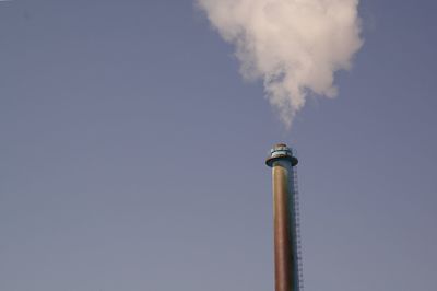 Low angle view of smoke emitting from chimney against sky