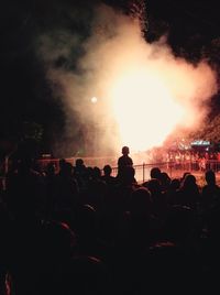 Crowd at music concert against sky at night