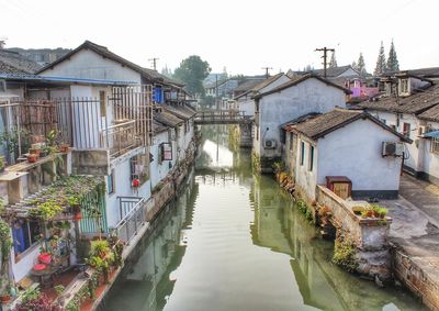 Canal amidst houses in town against sky