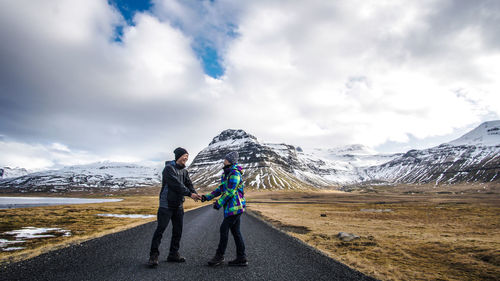 Full length of couple on road against snowcapped mountain 
