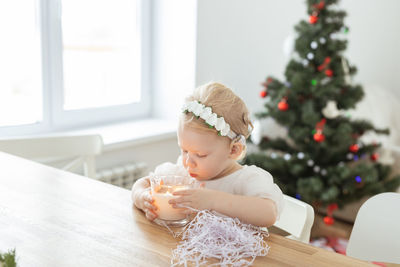 Portrait of smiling girl playing with christmas tree at home