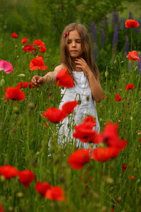 Portrait of young woman picking flowers on field