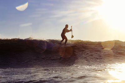 Male sup surfer at sunset time