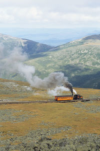 Steam locomotive pushing up coach to the summit of of mount washington at good weather conditions