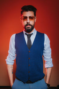 Portrait of mid adult man standing against red background