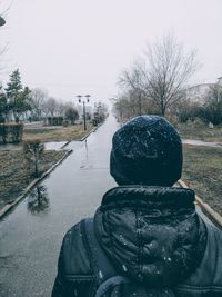 Rear view of person on snow covered landscape against sky