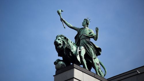Low angle view of angel statue against clear blue sky