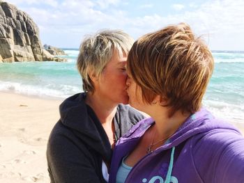 Close-up of mother and daughter on beach against sky