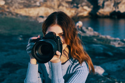 Portrait of young woman photographing camera