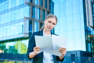 Elegant caucasian business woman in formal wear holds paper documents in her