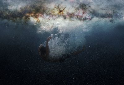 Double exposure of man falling in water and galaxy