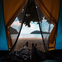 Low section of tent by sea against sky