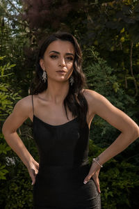 Portrait of beautiful young woman standing against tree