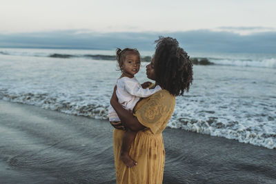 Full length of mother standing on beach against sea