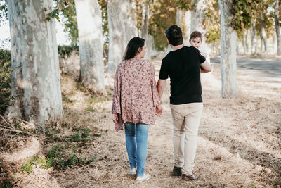 Rear view of man and woman standing by tree