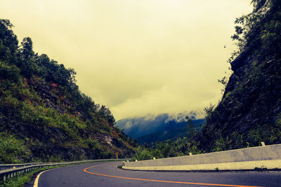 Road by trees against sky