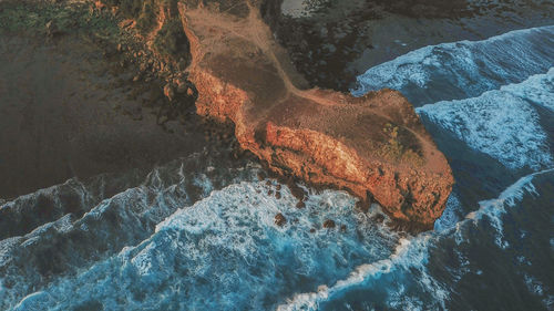 Aerial view of waves crashing on rocky coastline