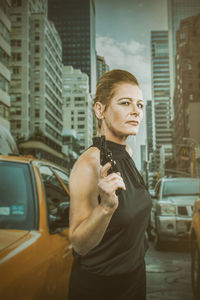 Portrait of woman holding gun while standing on city street