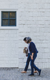 Adult daughter walking with her senior mother in city.