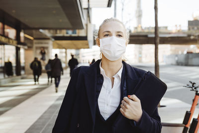 Businesswoman walking in street wearing face mask
