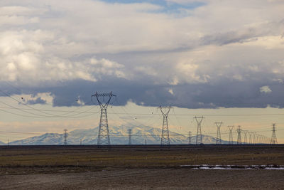 Electricity pylon on field against sky