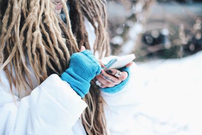 Midsection of woman holding smart phone during winter