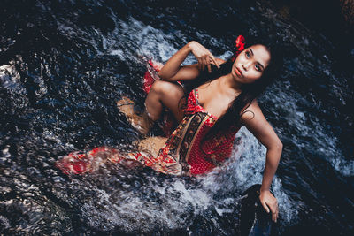 High angle view of young woman on rock at sea