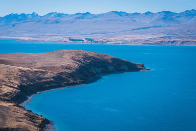 Scenic view of sea and mountains against blue sky