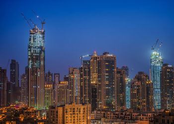 Illuminated buildings in city against sky
