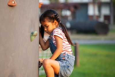 Side view of girl climbing wall at playground