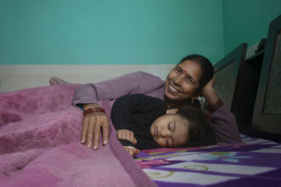 Portrait of grandmother with granddaughter sleeping on bed at home