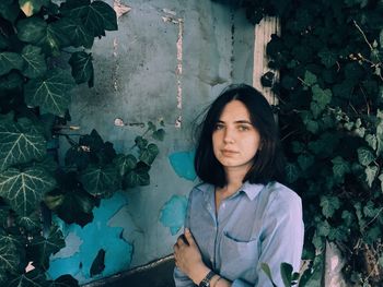 Portrait of young woman standing against plants