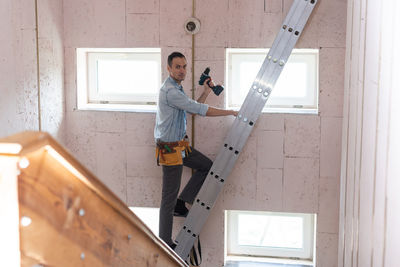 Side view of man standing on ladder