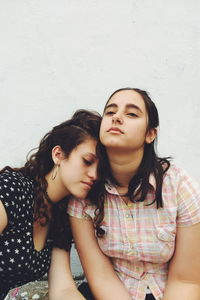 Female friends sitting against wall