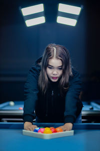 Portrait of young woman playing pool at home