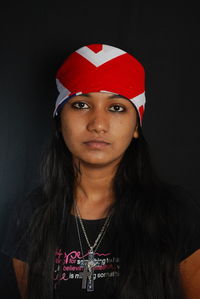 Portrait of woman wearing red hat against black background