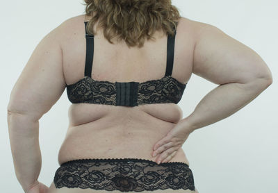 Rear view of shirtless young woman against white background