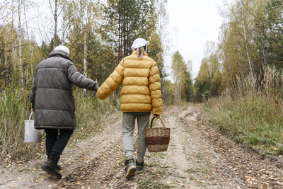Grandmother holding granddaughter's hand walking on footpath
