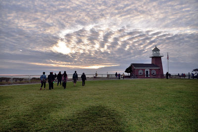 People on landscape against sky during sunset