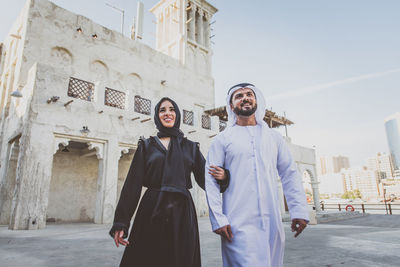 Low angle view of smiling couple walking on street in town