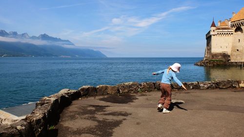 Rear view full length of girl standing by sea